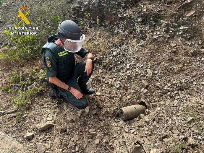 Un agente de la Guardia Civil retira el proyectil localizado en Cala en Porter.