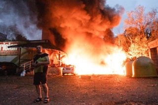 Archivo - July 31, 2025, Kyiv, Ukraine: A local resident walks past a fire following an air strike in Kyiv.