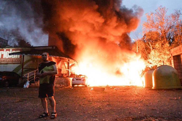 Archivo - July 31, 2025, Kyiv, Ukraine: A local resident walks past a fire following an air strike in Kyiv.