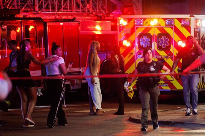 Archivo - July 2, 2025, Chicago, Illinois, USA: People walk near an ambulance while officers work the scene where four people were killed and 14 others were wounded in a shooting near the 300 block of West Chicago Avenue in the River North neighborhood.