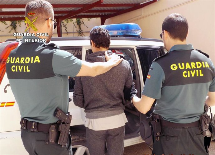 Uno de los detenidos es custodiado por dos agentes de la Guardia Civil
