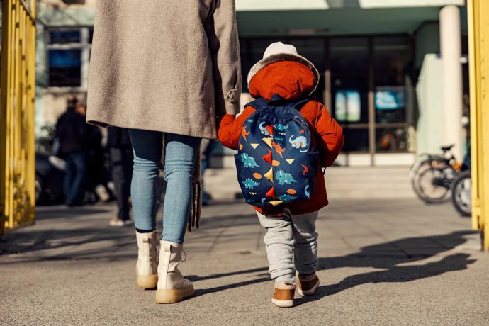 Un niño con mochila entrando al colegio.