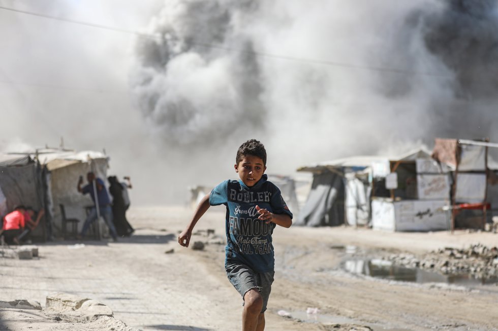 Un niño corre alejándose de un edificio residencial colapsado por un ataque aéreo de Israel en la ciudad de Gaza.