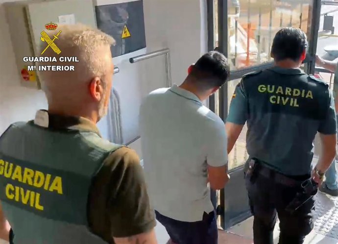 Uno de los detenidos es custodiado por dos agentes de la Guardia Civil