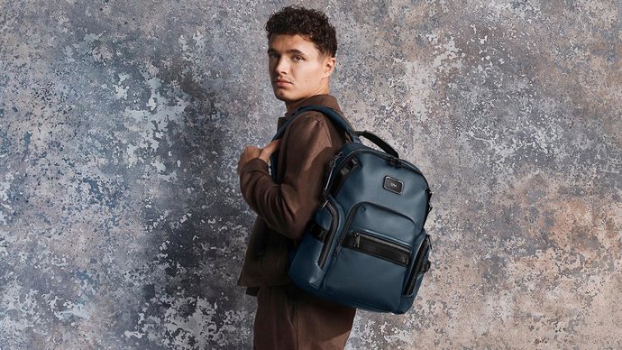 Lando Norris pictured with the Alpha Bravo Navigation Backpack in Navy Coated Canvas.