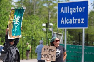 Archivo - July 19, 2025, Ochopee, Fl, US: Ashlie Soto of Lehigh Acres and Jill Cicero of Naples, Florida, hold up signs outside of Alligator Alcatraz on July 12, 2025, in Ochopee.