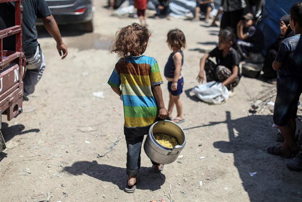 Palestinos esperan una entrega de alimentos por parte de una organización caritativa en medio de la ofensiva de Israel contra la Franja de Gaza y ante sus restricciones a la entrega de ayuda humanitaria (archivo)