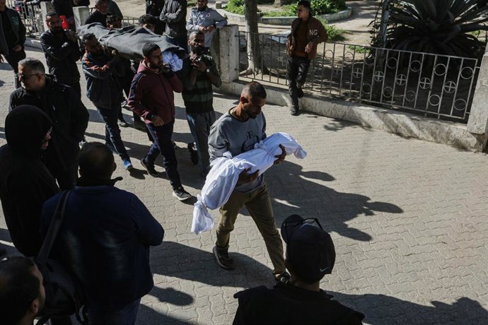 Archivo - 24 March 2025, Palestinian Territories, Gaza city: A family member carries the body of a dead child wrapped in a white sheet as mourners gather to receive bodies of the Palestinians killed in Israeli strikes, at Al-Ahli Arab Baptist hospital. Ph