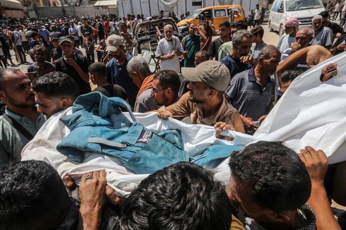 26 de agosto de 2025, Territórios Palestinos, Khan Younis: Palestinos carregam o corpo de um jornalista que foi morto em um ataque israelense ao Hospital Nasser em Khan Younis. A agência de defesa civil de Gaza disse que cinco jornalistas foram mortos ent