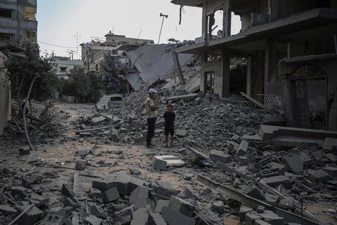 Civiles palestinos inspeccionan un lugar bombardeado por Israel en la Franja de Gaza