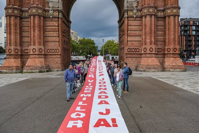 Representantes de sindicatos catalanes despliegan una pancarta ante el Arc de Triomf para apoyar la reducción de jornada laboral