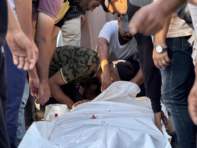 Archivo - Palestinos junto al cadáver de una persona muerta a causa de los ataques del Ejército de Israel contra la Franja de Gaza (archivo)