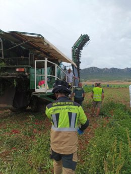 Bomberos junto a la cosechadora en la que la trabajadora ha resultado herida