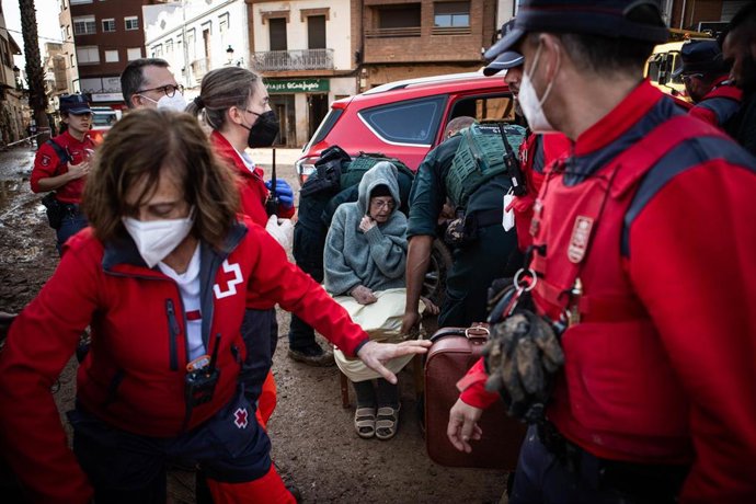 Archivo - Agentes de la Guardia Civil y miembros de la Cruz Roja evacúan a una persona afectada por la dana, en Paiporta.