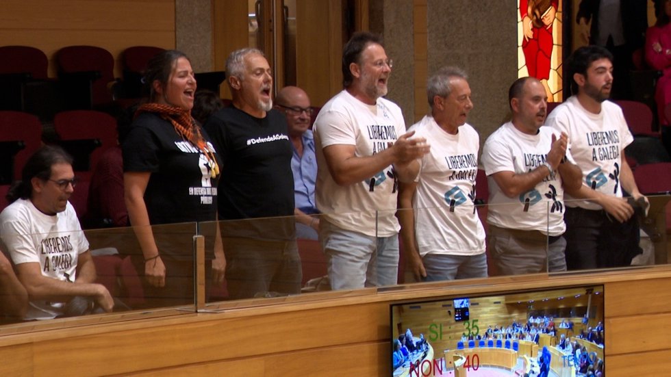 Seis miembros de la plataforma 'Por unha CRTVG ao Servizo do Pobo' lanzan proclamas desde la bancada del público del Parlamento gallego, ante la votación de una ILP por los medios de comunicación públicos.