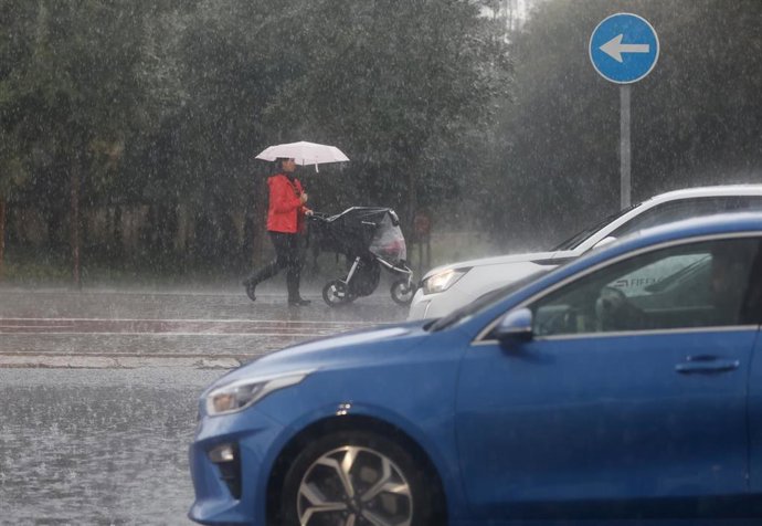 Archivo - Mujer se cubre con paraguas en València. Imagen de archivo.