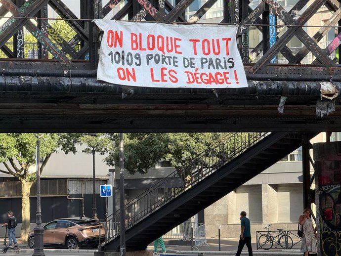 09 de setembro de 2025, França, Paris: Uma faixa com os dizeres "On bloque tout" (Vamos bloquear tudo) está pendurada em uma ponte ferroviária em Paris. O slogan se espalha após a apresentação de um orçamento de austeridade pelo governo anterior, que é de