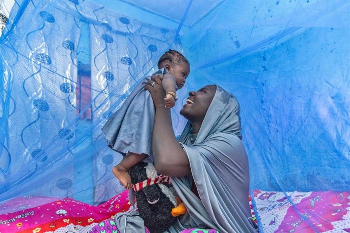 Ummi Inuwa e sua filha Ammi sentam-se sob um mosquiteiro tratado com inseticida em sua casa no estado de Kaduna, na Nigéria.