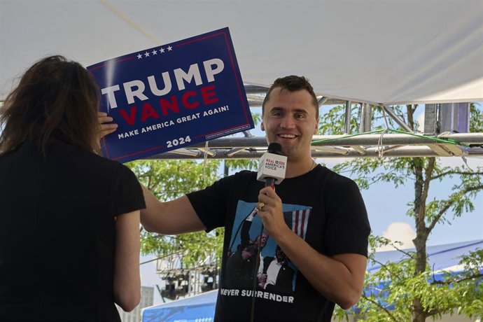 Archivo - El comentarista conservador estadounidense Charlie Kirk muestra una pancarta en apoyo a la candidatura de Donald Trump a la Presidencia de Estados Unidos