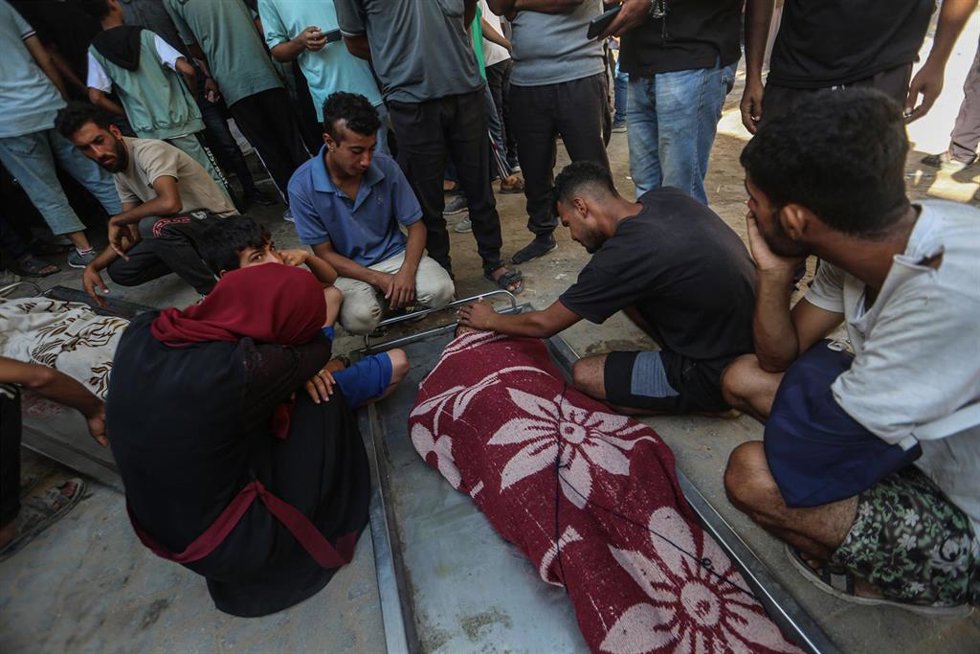 Palestinos junto a un muerto a causa de los ataques ejecutados por el Ejército de Israel contra la Franja de Gaza (archivo)