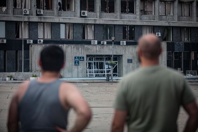 Moradores de Sumi (Ucrânia) observam os danos causados por um drone russo no prédio administrativo regional.