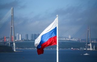 RUSSIA, VLADIVOSTOK - SEPTEMBER 4, 2025: A Russian flag flies against a backdrop of Russky Bridge over the Eastern Bosphorus Strait
