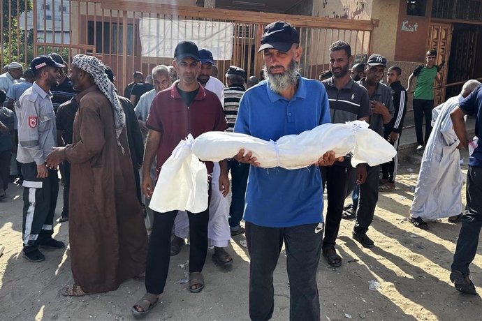 Palestinos con el cadáver de un niño muerto por desnutrición a causa de la ofensiva de Israel y sus restricciones a la entrega de ayuda a la Frania de Gaza antes de su entierro en Jan Yunis (archivo)