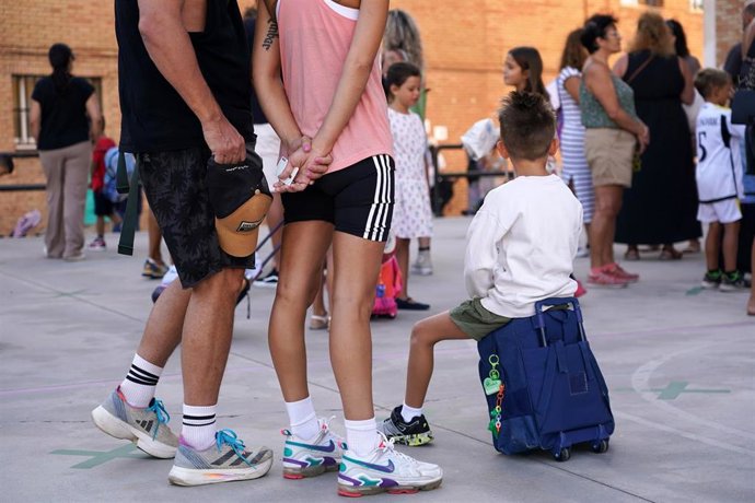 Archivo - Niños y padres hacen cola para entrar al colegio el primer día de clase tras la vacaciones de verano.