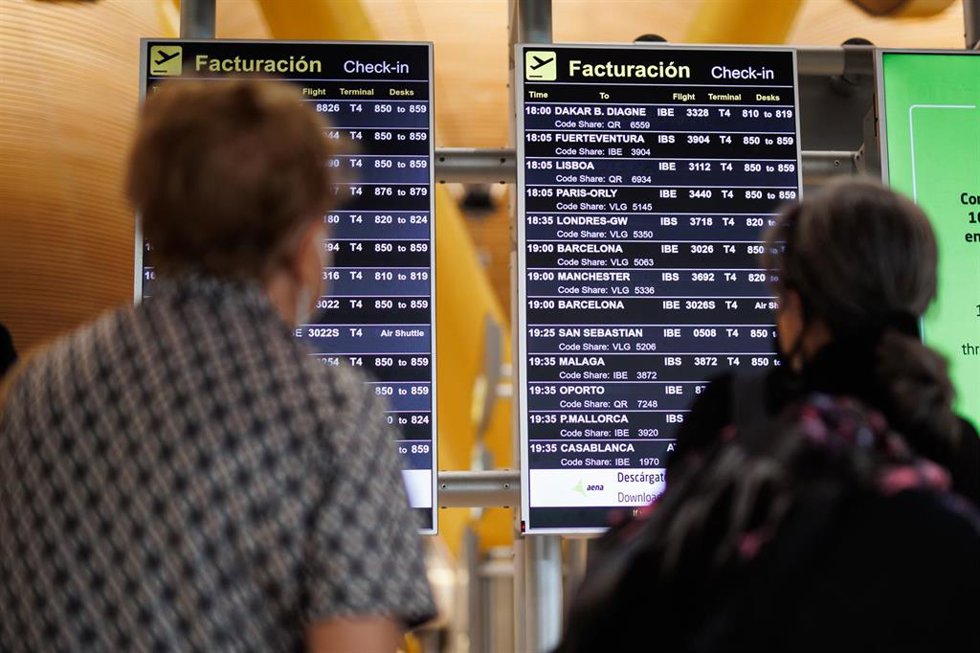 Archivo - Dos personas miran el panel de facturación de la Terminal 4 (T4) del aeropuerto Adolfo Suárez Madrid-Barajas