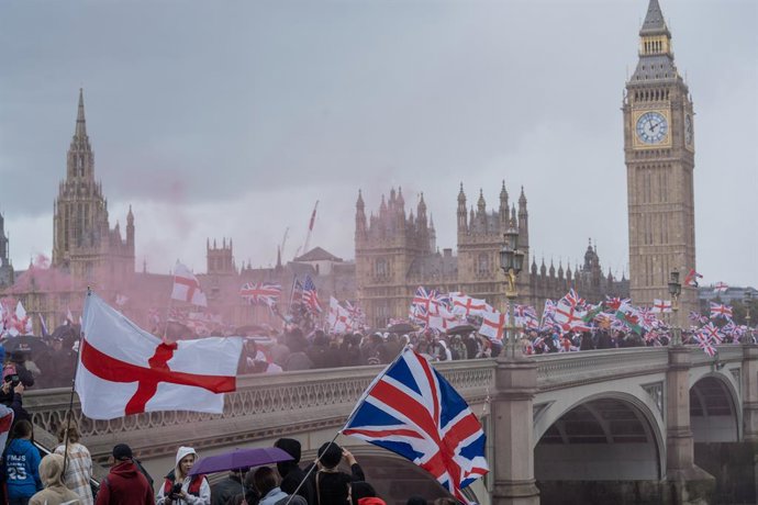 13 de setembro de 2025, Londres, Reino Unido: Patriotas cruzam a ponte de Westminster segurando bandeiras da Union Jack durante a manifestação. Milhares de apoiadores de Tommy Robinson se reuniram no centro de Londres para a mais recente manifestação de d