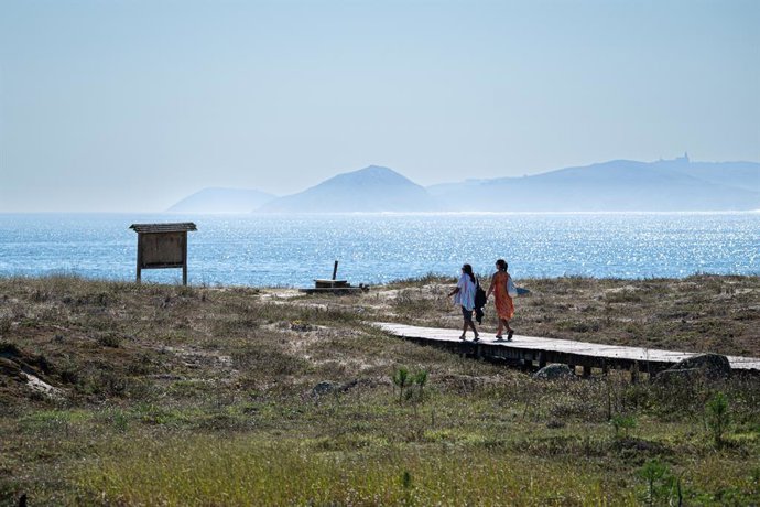 Archivo - Dos personas se dirigen a la playa Silgar, a 30 de septiembre de 2023, en Sanxenxo, Pontevedra, Galicia (España). Septiembre dará paso a un octubre inmerso en un episodio de calor, con un veranillo de San Miguel, al coincidir con dicha festivida