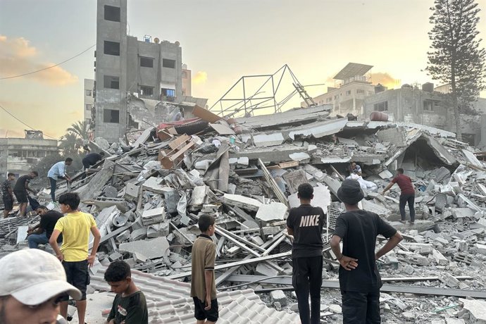 TERRITÓRIOS PALESTINOS, FAIXA DE GAZA - 15 DE SETEMBRO DE 2025: Pessoas se reúnem do lado de fora de um prédio danificado em um ataque aéreo israelense a oeste da Cidade de Gaza