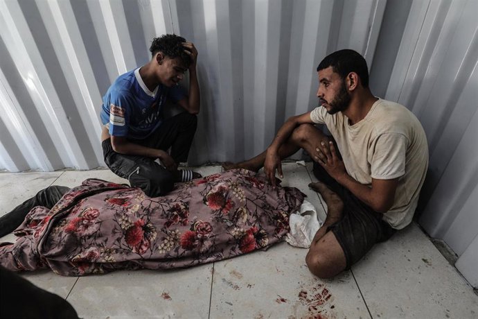 Palestinos junto al cadáver de una persona tiroteada por las fuerzas de Israel cuando intentaba obtener ayuda humanitaria en la Franja de Gaza (archivo)