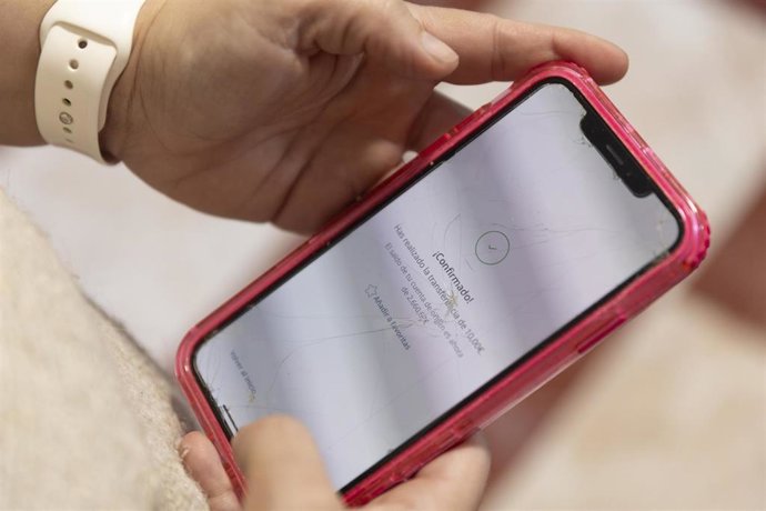 Archivo - Una mujer realiza una transferencia bancaria con su teléfono móvil, a 10 de enero de 2025, en Madrid (España). 