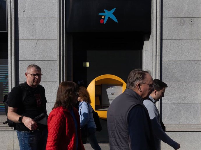 Archivo - Varias personas pasan delante de un cajero CaixaBank, a 6 de noviembre de 2024, en Madrid (España). 