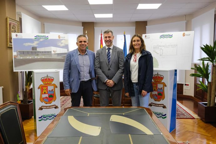 El consejero de Deporte, Luis Martínez Abad, y el alcalde de Argoños, Juan José Barruetabeña, visitan los terrenos donde se ubicará el futuro polideportivo del municipio y muestran la infografía de la instalación