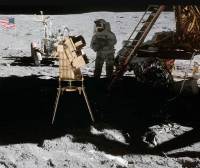 O astronauta da Apollo 16, John Young, é fotografado na superfície lunar com a câmera/espectógrafo ultravioleta distante banhado a ouro de George Carruthers, o primeiro observatório baseado na Lua.