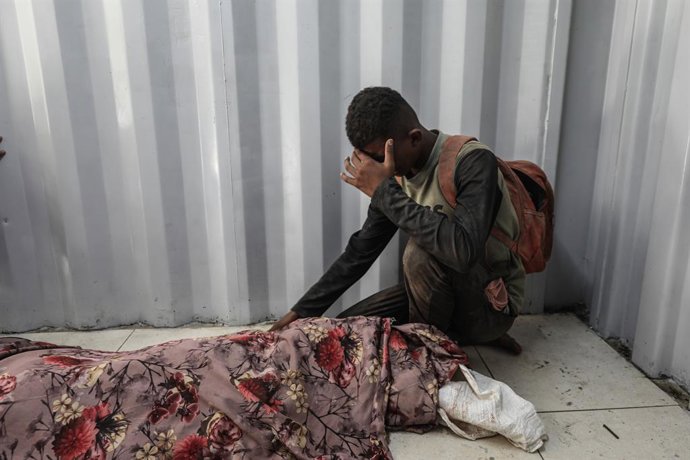 Um palestino no Hospital Al Auda, no campo de refugiados de Nuseirat, ao lado do corpo de uma pessoa morta a tiros pelo exército israelense durante sua ofensiva contra a Faixa de Gaza (arquivo).