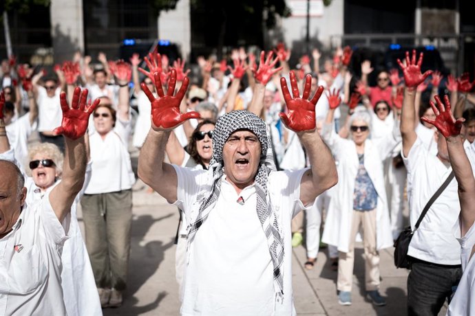 Dezenas de pessoas com as mãos pintadas de vermelho durante uma homenagem aos profissionais de saúde que trabalham em Gaza, em frente ao Museu de Arte Contemporânea (MARCO), em 20 de setembro de 2025, em Madri (Espanha). A PararLaGuerra.es organizou uma a