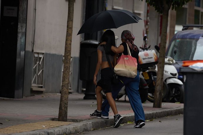 Archivo - Dos mujeres se protegen de la lluvia con un paraguas, a 8 de junio de 2024, en Madrid (España). La llegada de una Depresión Aislada en Niveles Altos (DANA) a España va a provocar durante el fin de semana y hasta el jueves de la semana que viene 