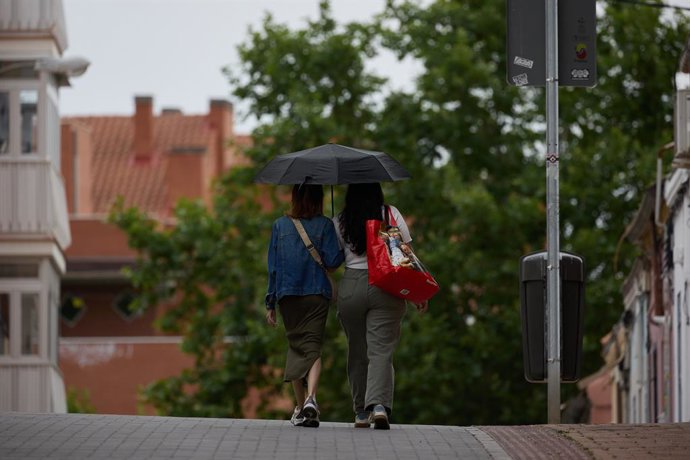 Archivo - Dos mujeres se protegen de la lluvia con un paraguas, a 8 de junio de 2024, en Madrid (España). La llegada de una Depresión Aislada en Niveles Altos (DANA) a España va a provocar durante el fin de semana y hasta el jueves de la semana que viene 