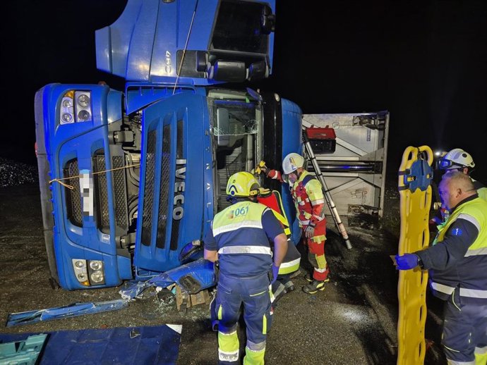 Bomberos excarcelan a un conductor de un camión volcado.