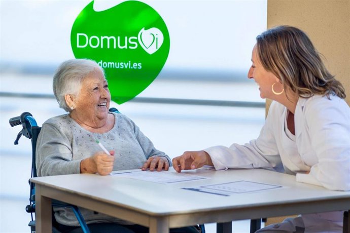 Una mujer sonríe junto a una sanitaria en una residencia de DomusVi, en una imagen de archivo.