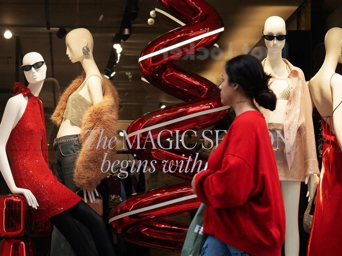 Archivo - Una mujer pasa por un escaparate durante la campaña de Navidad, en una imagen de archivo.