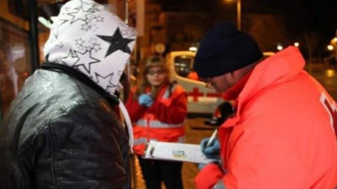 Archivo - Voluntarios de Cruz Roja atienden a una persona sin hogar.- Archivo