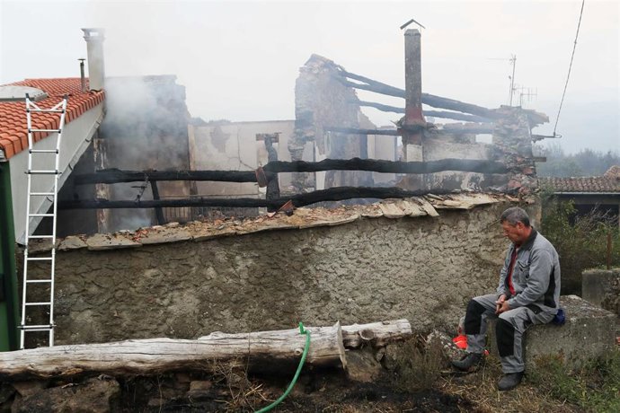 Una persona junto a una casa calcinada, a 20 de septiembre de 2025, en Pantón, Lugo, Galicia.