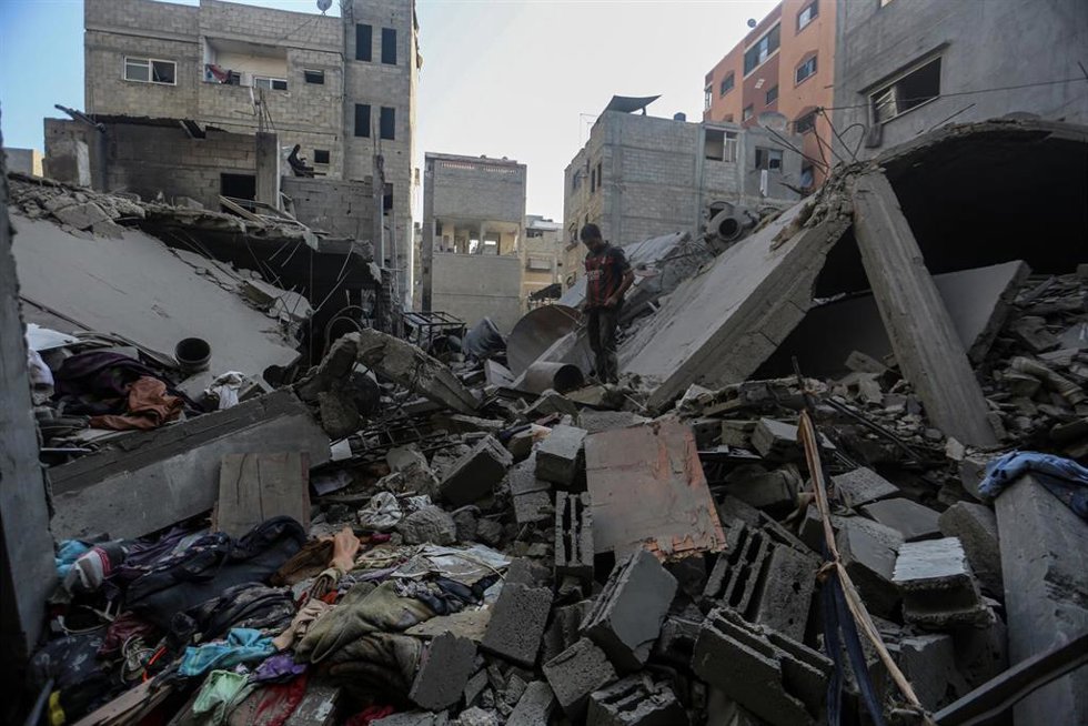 Civiles palestinos entre los escombros de un edificio en la Franja de Gaza