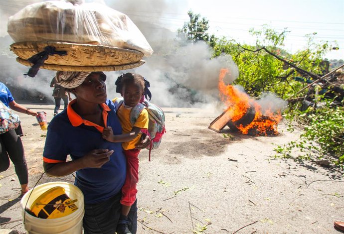 Archivo - Arquivo - Uma mulher passa por uma barricada durante um protesto contra a insegurança na capital do Haiti, Porto Príncipe (arquivo).