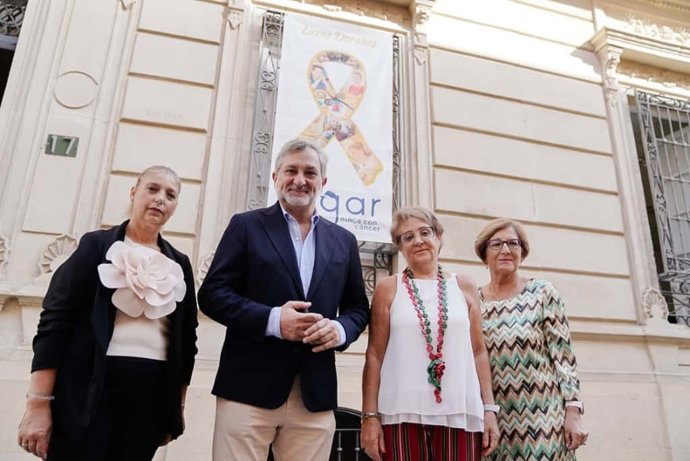 El vicepresidente de la Diputación de Almería Ángel Escobar junto a la presidenta de Argar, Rosa Onieva, y miembros de la asociación, ante el lazo dorado instalado en la fachada del Palacio Provincial.