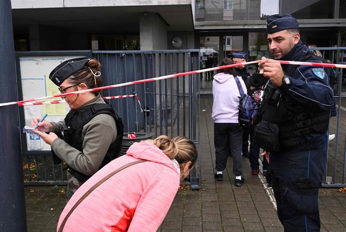 24 September 2025, France, Benfeld: French gendarmes and police officers let parents of students into the Robert Schuman high school after a teacher was stabbed by a student with a sharp weapon. A 14-year-old teenager was arrested after attacking a 66-yea